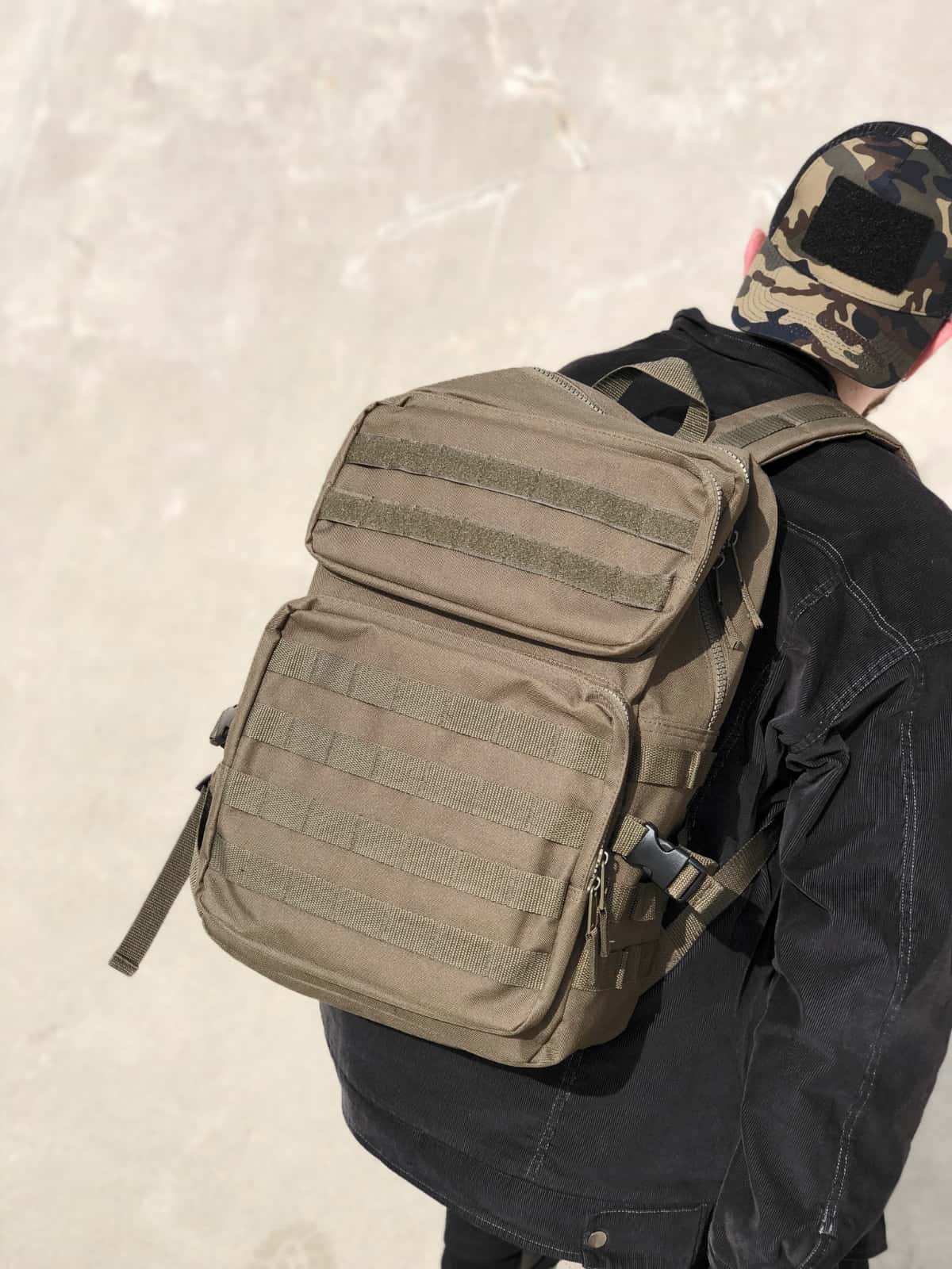 Model wearing the Tactical Bag in military green and the Plain Cap in camo